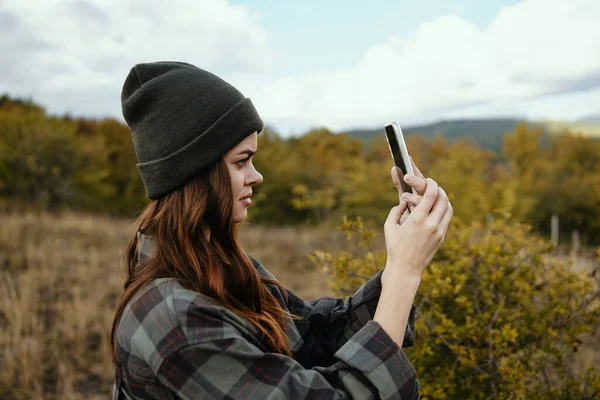 Porträtt av en kvinna i medicinsk mask med en telefon på bakgrunden av en höstskog i naturen — Stockfoto