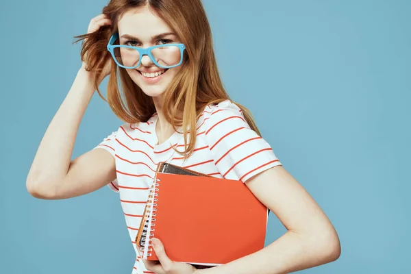 Menina em óculos de moda com cadernos em mãos em um fundo azul corte vista Copiar Espaço — Fotografia de Stock