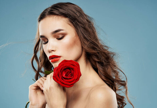 Passionate woman with red rose eye shadow on eyelids blue background cropped view