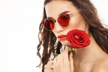 Kırmızı gül ve güneş gözlüklü, çıplak omuzlu esmer kız.