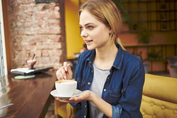 커피를 마시며 아침 식사를 하고 카페 테이블에 앉아 있는 아름다운 여성 — 스톡 사진