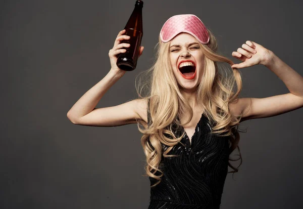 Mulheres com uma máscara de sono rosa seguram uma garrafa de cerveja na mão — Fotografia de Stock