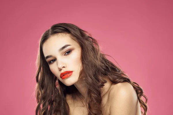 Attraktive Frau modische Frisur entblößte Schultern und rote Lippen rosa Hintergrund — Stockfoto