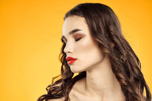 Schöne Brünette nackte Schultern helles Make-up rote Lippen Frisur Nahaufnahme gelber Hintergrund — Stockfoto