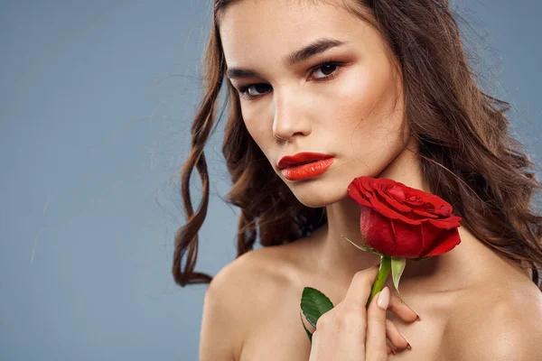 Nő portré vörös rózsa közel az arc szürke háttér és smink göndör haj — Stock Fotó