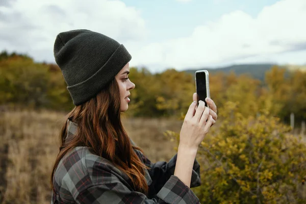 Mujer con teléfono móvil en el bosque de otoño y montañas en el fondo — Foto de Stock