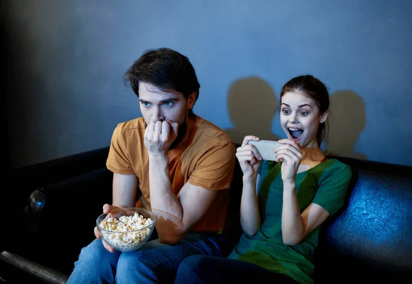 Homens e mulheres no sofá Em uma sala escura assistindo a um filme de terror — Fotografia de Stock