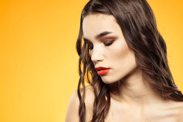 Vacker brunett nakna axlar ljusa makeup röda läppar frisyr närbild gul bakgrund — Stockfoto