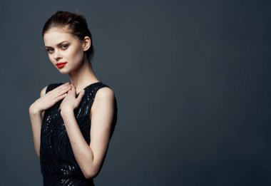 Gri arkaplanda poz veren siyah elbiseli kızıl saçlı kadın Boşluğu Kopyala