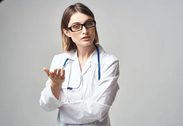 Läkare med stetoskop visar handen åt sidan på en grå bakgrund Kopiera utrymme — Stockfoto