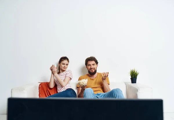 Νεαρός άνδρας και γυναίκα βλέποντας τηλεόραση με ποπ κορν στον καναπέ και κόκκινο καρό πράσινο λουλούδι — Φωτογραφία Αρχείου