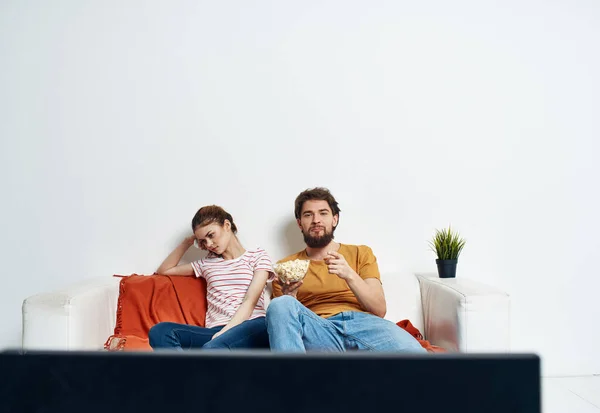 Άντρας και γυναίκα στον καναπέ να βλέπουν τηλεόραση με λουλούδια. — Φωτογραφία Αρχείου