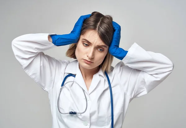 感情的な女性で青医療手袋タッチ彼女の頭とともに彼女の手 — ストック写真