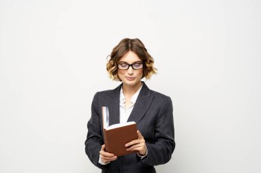 Not defteri ve gözlüklü bir iş kadını takım elbise modelinin hafif arka planında çalışıyor..