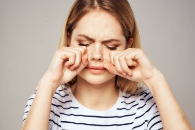 Çizgili tişörtlü bir kadın ellerini duygularının önünde tutar hoşnutsuz arka plan