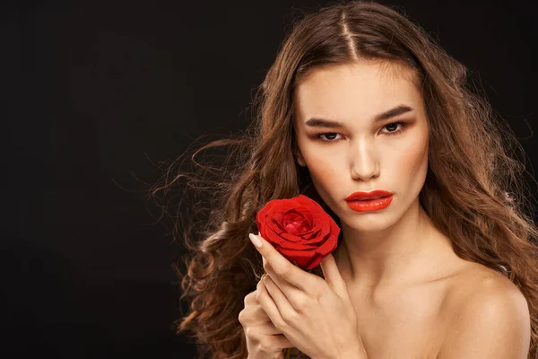 Femme avec une rose rouge sur un fond sombre cheveux longs maquillage lèvres rouges — Photo