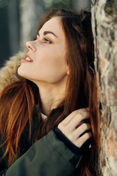 Mujer bonita mira a un lado cerca de un árbol en la naturaleza aire fresco —  Fotos de Stock