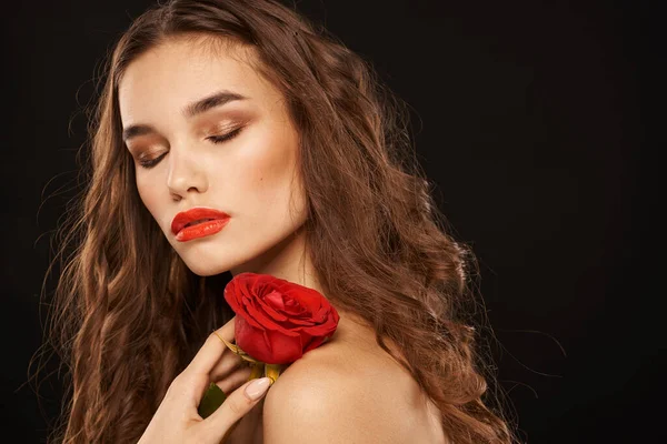 Kobieta z czerwoną różą na ciemnym tle długie włosy makijaż czerwone usta — Zdjęcie stockowe
