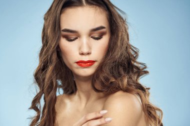 Güzel bir kadın. Çıplak omuzlar. Saç bakım, parlak makyaj, mavi arka plan.