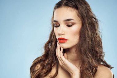 Zarif esmer, modaya uygun, parlak, makyajlı, çıplak omuzlar yakın plan, mavi arka plan.