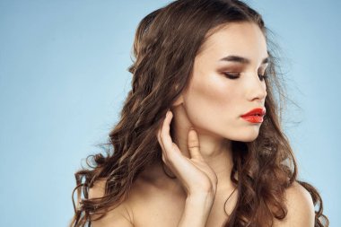 Zarif esmer, modaya uygun, parlak, makyajlı, çıplak omuzlar yakın plan, mavi arka plan.