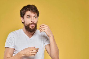 Beyaz tişörtlü sakallı adam duyguları yakın plan eğlenceli sarı arka plan