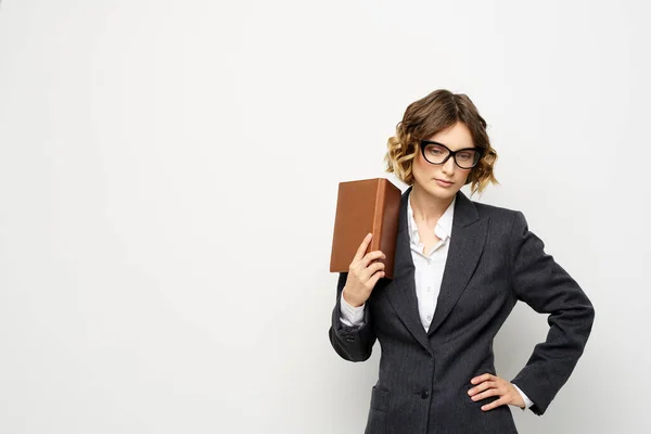 Klasik takım elbiseli bir iş kadını elinde bir not defteri ve yüzünde gözlüklerle. — Stok fotoğraf
