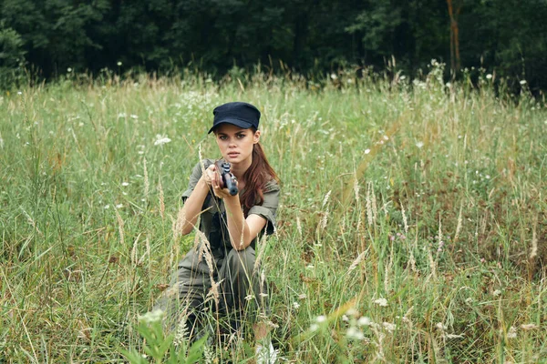 무기를 들고 검은 모자푸른 잎을 든 채 풀 위에 앉아 있는 군인 여자 — 스톡 사진