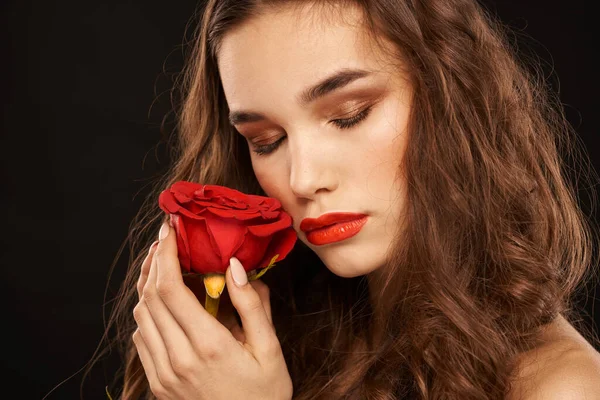 Donna con una rosa rossa su uno sfondo scuro trucco capelli lunghi labbra rosse — Foto Stock