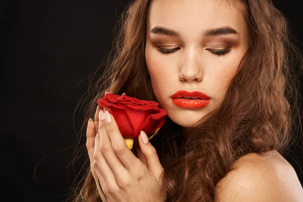 빨간 장미를 들고 어두운 배경에 긴 머리를 한 여자가 붉은 입술을 구성하고 있다 — 스톡 사진