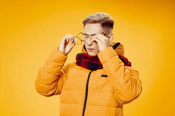 Egy sárga kabátos fickó szemüveget tart a látáshoz elszigetelt háttérrel — Stock Fotó