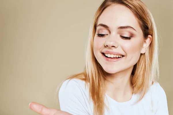 Donna allegra in un bianco gesti T-shirt con le mani emozioni sfondo beige — Foto Stock