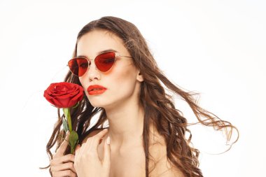 Kırmızı gül ve güneş gözlüklü, çıplak omuzlu esmer kız.