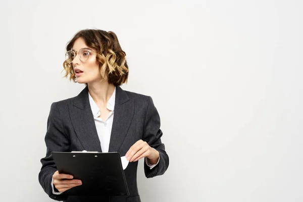 Üzletasszony egy öltöny dokumentumok a kezében könnyű háttér göndör haj frizura — Stock Fotó