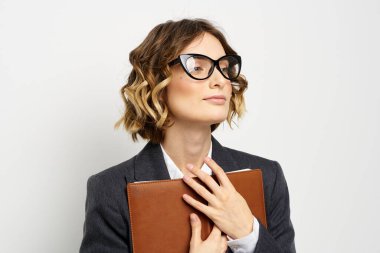 Klasik takım elbiseli bir iş kadını elinde bir not defteri ve yüzünde gözlüklerle.