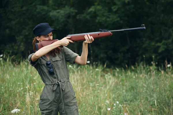 Woman With weapons in hand, nature takes aim green overalls — Stock Photo, Image