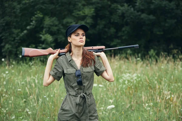 등 뒤에서 녹색 점프 복 사냥검은 모자 뒤에 총을 들고 있는 여자 — 스톡 사진