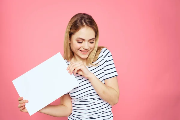 Femme tenant une feuille blanche dans ses mains rayé t-shirt émotions fond rose — Photo