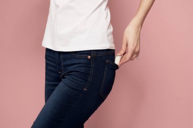 Elinde tampon, elinde hijyen, beyaz tişört, kot, pembe arka plan adet döngüsü olan bir kadın.