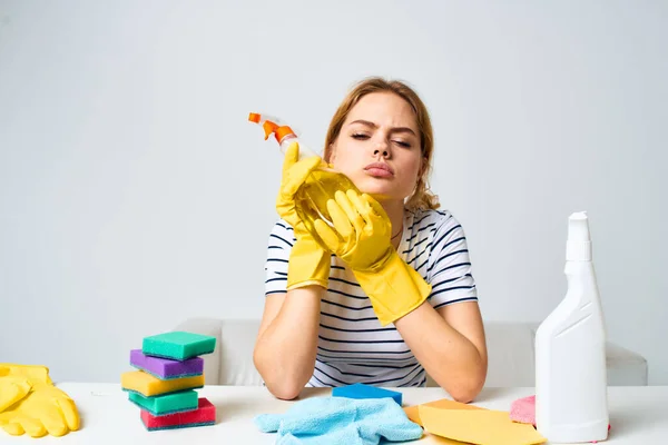 Mujer sentada en la mesa detergente trapos esponjas casa cuidado interior luz fondo — Foto de Stock