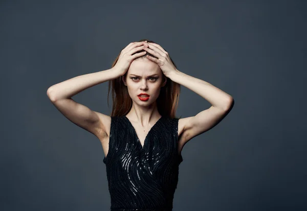 Emotionale Frau berührt ihren Kopf mit Händen und schwarzem Kleid Modell grauen Hintergrund — Stockfoto