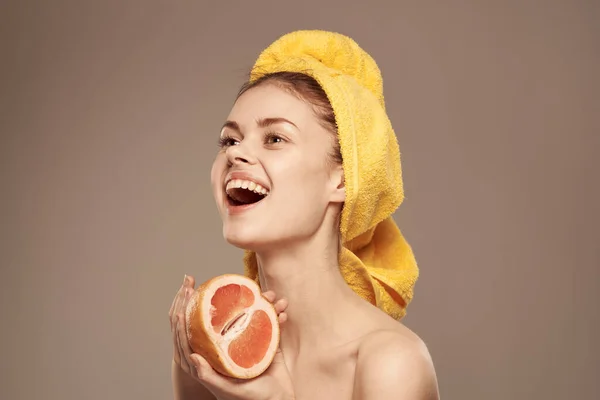 Donna con un asciugamano sulla testa pompelmo nelle mani salute vitamine spalle scoperte — Foto Stock