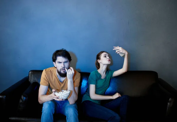 Emotionale Frau und Mann mit einem Teller Popcorn, die abends drinnen fernsehen — Stockfoto