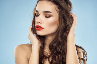 Zarif esmer, modaya uygun, parlak, makyajlı, çıplak omuzlar yakın plan, mavi arka plan.