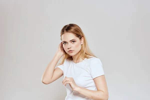 Vidám szőke egy fehér póló gesztikuláló kezével világos háttér — Stock Fotó
