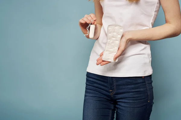 Lány egy tampon és egy pad a kezében egy kék háttér higiéniai tisztaság menstruáció — Stock Fotó