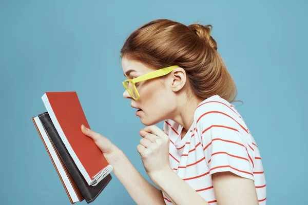 Mooie vrouwelijke student met notitieblokken en in gele bril op een blauwe achtergrond onderwijs wetenschappelijk instituut — Stockfoto