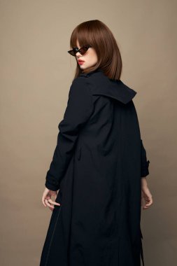 Zarif kemer takan güzel kadın ceketi bej arka planda eğleniyor. 