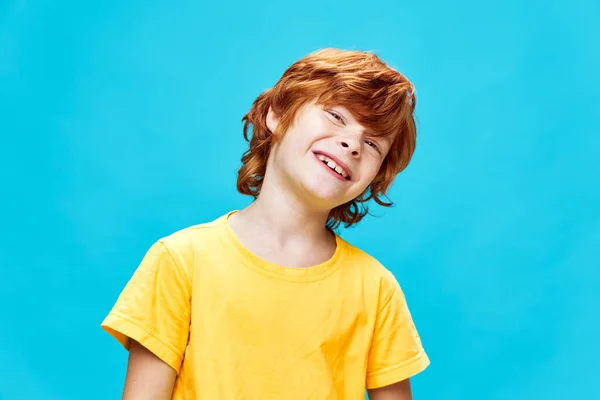 Pelirrojo chico inclinó su cabeza a un lado sonrisa amarillo camiseta estudio — Foto de Stock