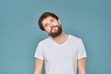 Beyaz tişörtlü, el kol hareketleri yapan, stüdyosu kesilmiş biri.